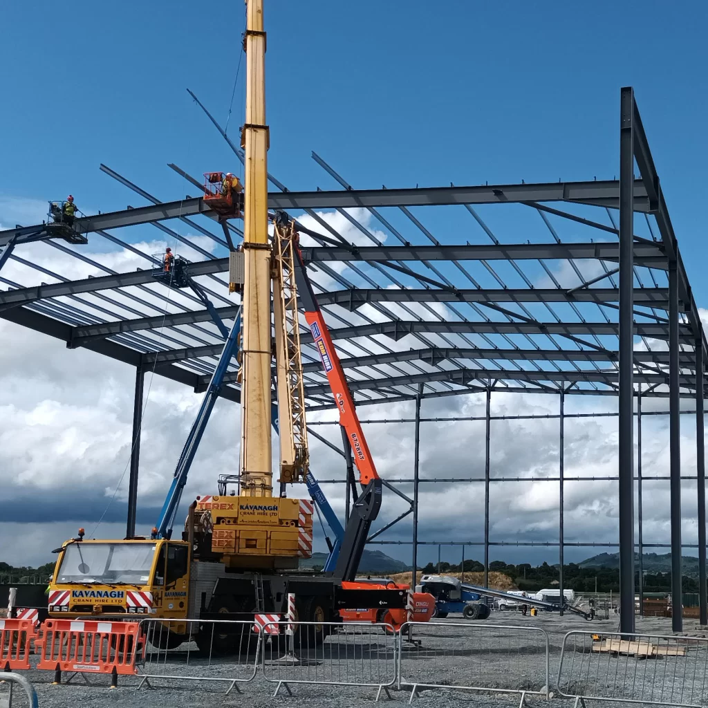 Steel frame of a farm shed under construction with crane