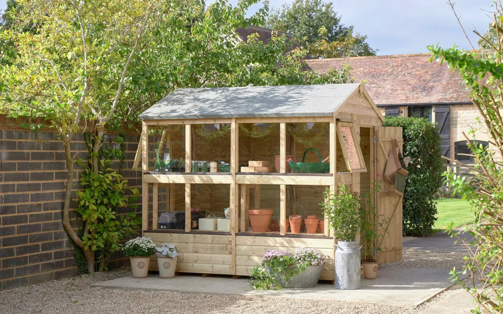 A charming wooden garden shed under the dappled shade of a tree