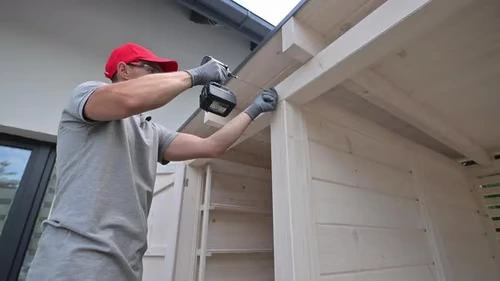 homeowner using a drill to build a shed